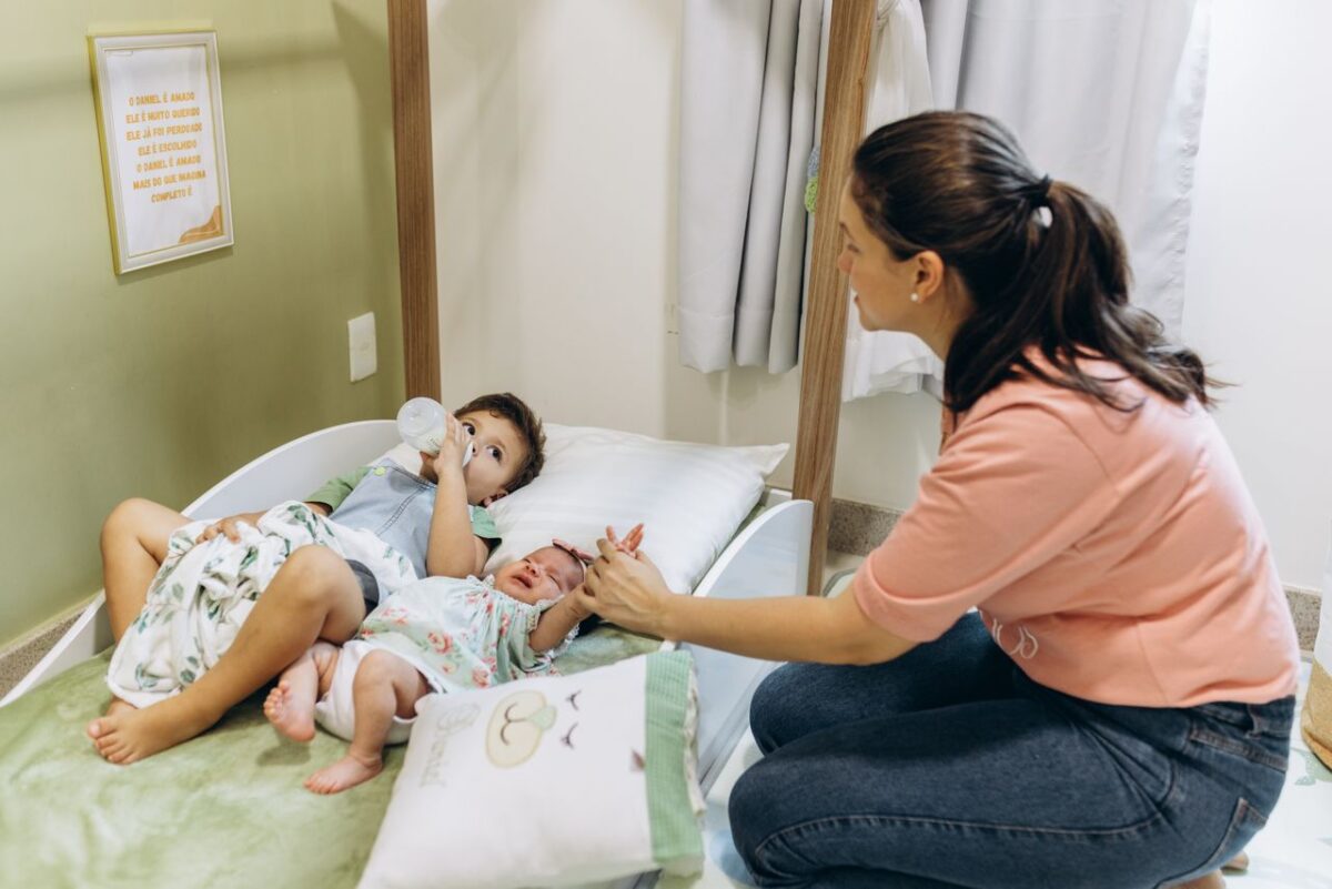 À propos A mother sits with her children on a bed, fostering a warm and nurturing atmosphere.