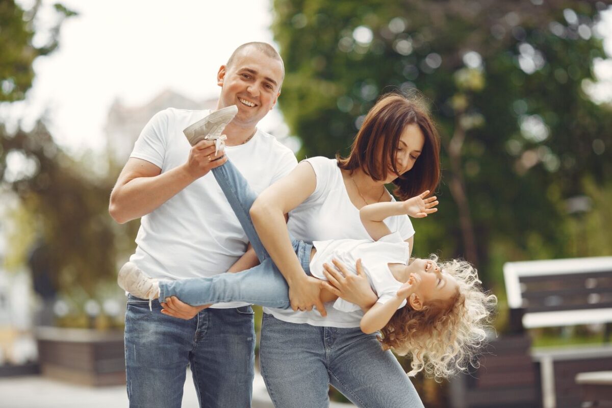 À propos Happy family enjoying playful moments outside on a sunny day.